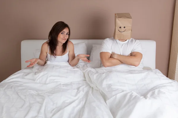 Funny situation in bed. Man with paper bag over head — Stock Photo, Image