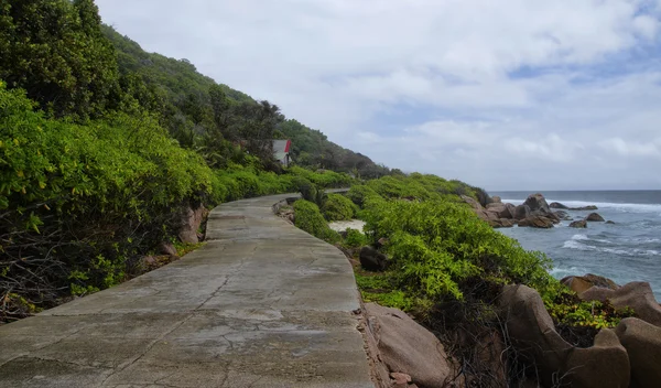 Pasang surut di pantai timur liar La Digue, Seychelles dengan satu-satunya jalan di latar depan — Stok Foto