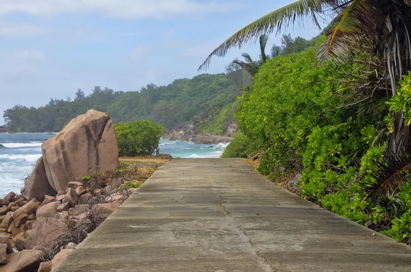 Ebbe an der wilden Ostküste von la digue, Seychellen mit der einzigen Straße im Vordergrund — Stockfoto