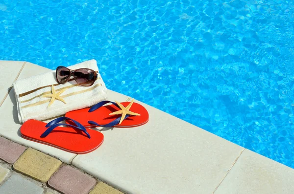 Chanclas, gafas de sol, toalla, estrellas de mar en la piscina . —  Fotos de Stock