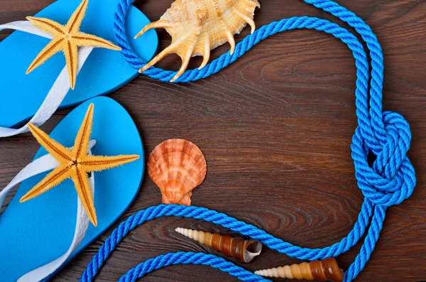 Flip-flops, starfish and seashells on a wooden background. — Stock Photo, Image