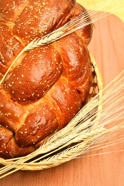 Pane fresco e grano sulla tavola di legno — Foto Stock