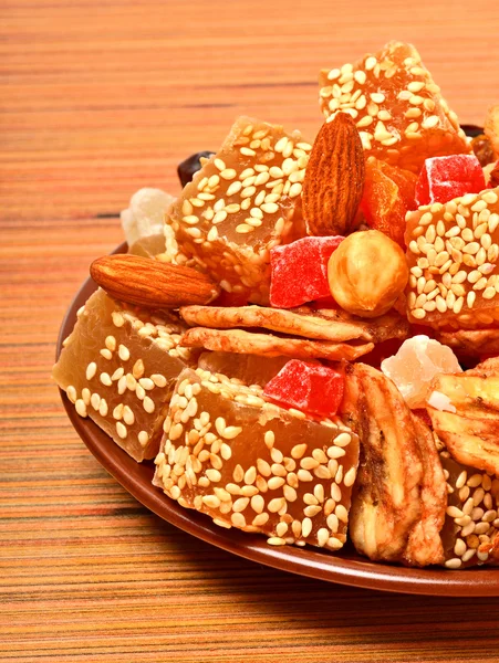 Turkish sweet delights with sesame, dried bananas, candied fruits on the plate on wood — Stock Photo, Image