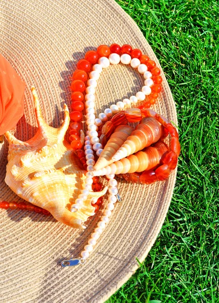 Chapeau élégant, collier de perles, perles, coquillages sur l'herbe — Photo