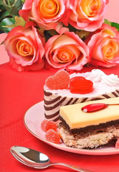 Pasteles de San Valentín, tartas y rosas rojas en el mantel rojo — Foto de Stock