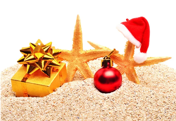 Seesterne, Christbaumkugel und eine Geschenkbox im Sand — Stockfoto