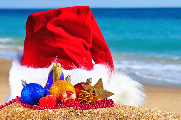 Kerstmuts met gekleurde kerstballen aan de kust — Stockfoto