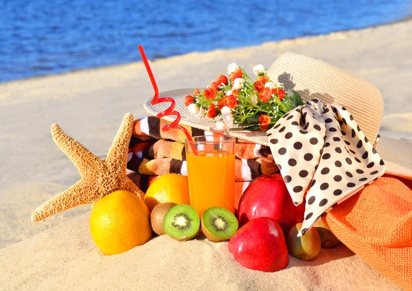 Cappello donna, frutti diversi, stelle marine e bicchiere di succo sul — Foto Stock