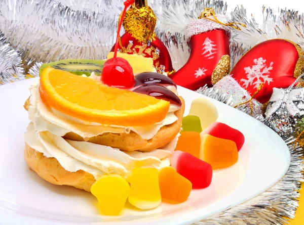Torta di frutta natalizia con crema su piatto bianco e fili d'argento — Foto Stock