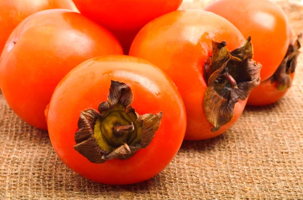 Heap of riipe persimmon fruits on sacking background — Stock Photo, Image