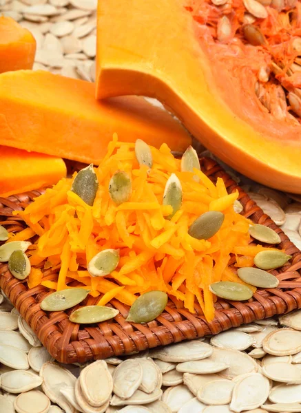 Ripe raw pumpkin with grated pumpkin and pumpkin seeds background — Stock Photo, Image