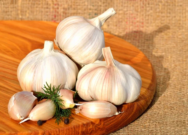 Bio-Knoblauch in einer Holzschüssel auf dem Schneidebrett — Stockfoto