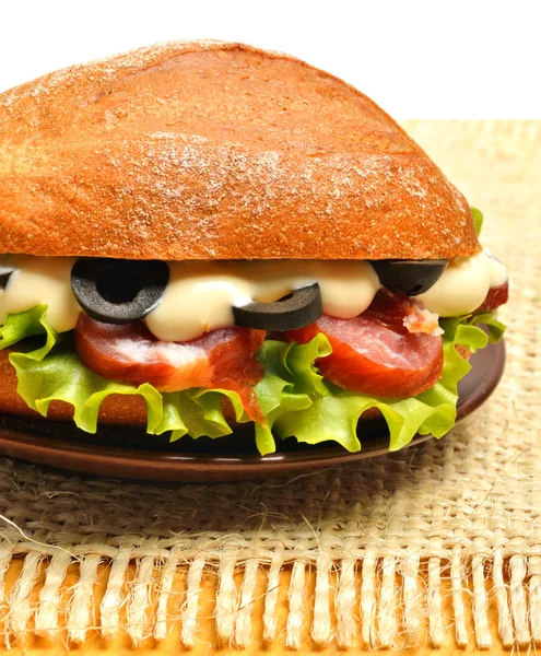 Sabroso sándwich fresco con lechuga verde, jamón y aceitunas en el s —  Fotos de Stock