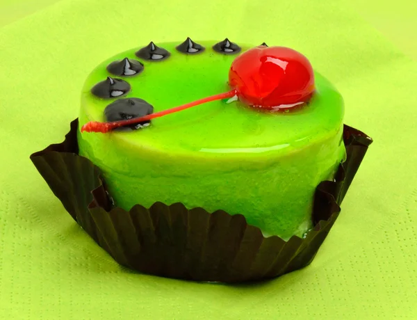 Vynikající zelený dort s třešničkou na zelený ubrousek na černém plátu — Stock fotografie