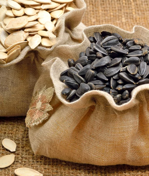 Pumpkin seeds and sunflower seeds in the bags  on sacking backgr — Stock Photo, Image