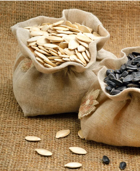 Pumpkin seeds and sunflower seeds in the bags on sacking backgro — Stock Photo, Image