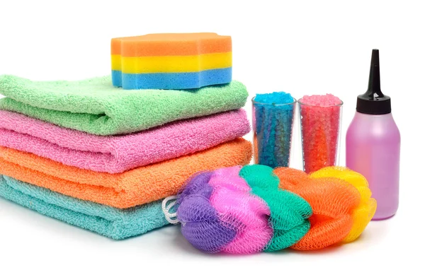 Colorful stacked spa towels, sea salt, mop and shampoo bottle is — Stock Photo, Image