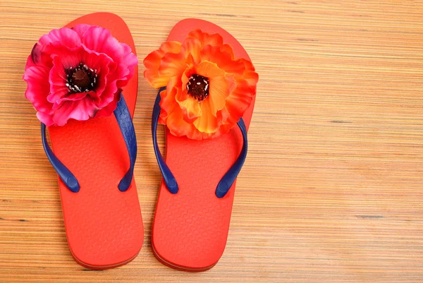红拖鞋，拖鞋用木制的背景上鲜花 — 图库照片