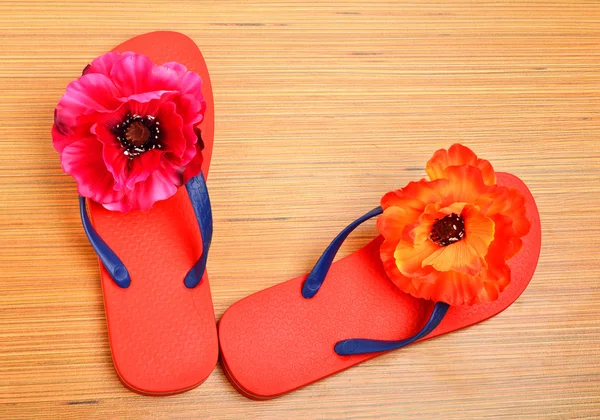 Rode slippers, sloffen met bloemen op het hout — Stockfoto