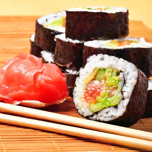 Sushi, Rollen, Ingwer und Essstäbchen auf Bambusmatte — Stockfoto