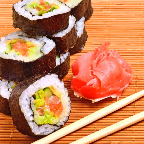 Sushi, Rollen, Ingwer und Essstäbchen auf Bambusmatte — Stockfoto