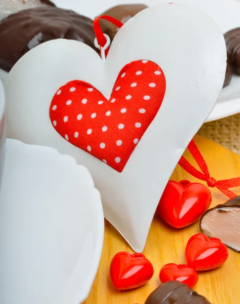 Chocolate candies and a valentine heart on white plate on wooden — Stock Photo, Image