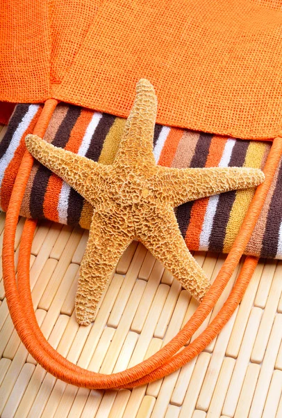 Bolsa de praia com toalha e estrela do mar em um fundo de madeira — Fotografia de Stock