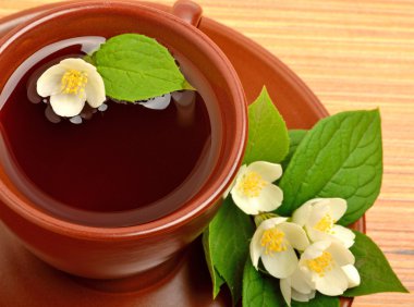 Seramik bardak çay ile ahşap üzerine Yasemin çiçeği