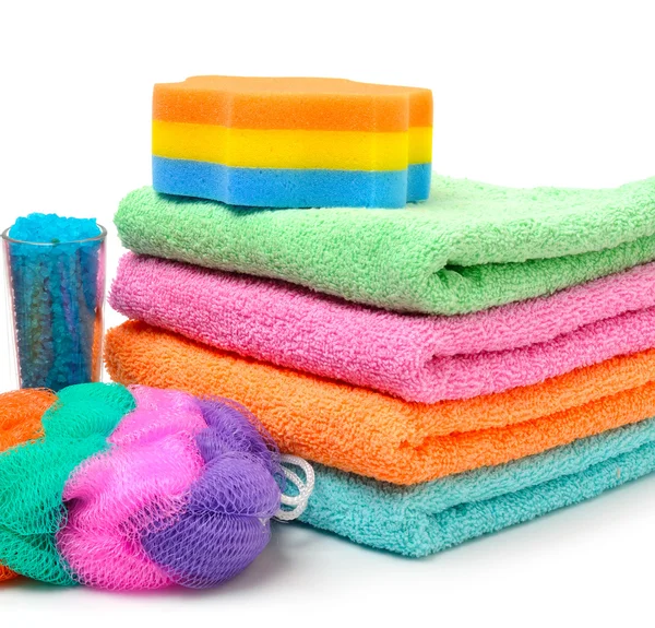 Colorful stacked spa towels, sea salt, mop and shampoo bottle is — Stock Photo, Image