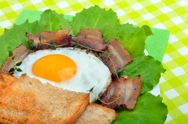 Bacon with sunny side up eggs served with toasts — Stock Photo, Image