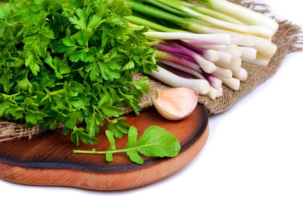 Prezzemolo, cipolla verde, aglio, insalata di rucola sul tagliere — Foto Stock