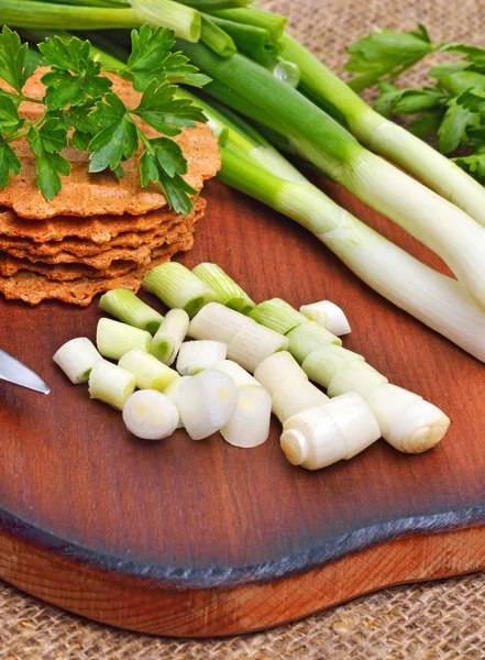 Gehackte grüne Zwiebel mit Knäckebrot auf Schneidebrett — Stockfoto