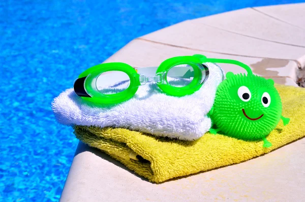 Bath towels, goggles, toy agains blue wate — Stock Photo, Image