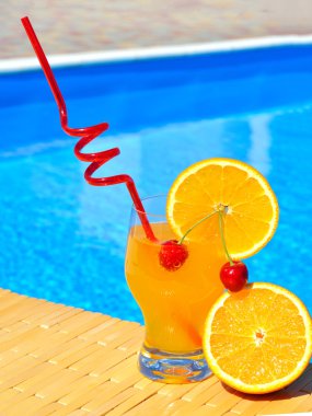 Cocktail with orange and cherry on pool background