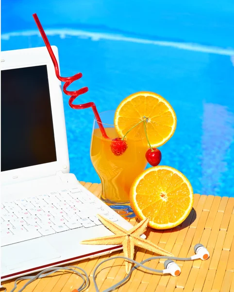 Cocktail, laptop and starfish on pool background — Stockfoto