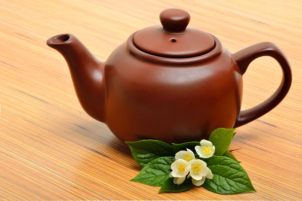 Teapot and jasmine flower twig on wooden background — Stock Photo, Image