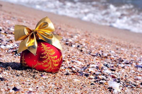 Kum plajı üzerinde altın yay ile Noel biblo — Stok fotoğraf