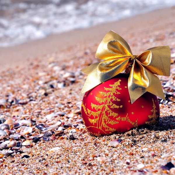 红色与金色的蝴蝶结在沙滩上的圣诞小玩意 — 图库照片