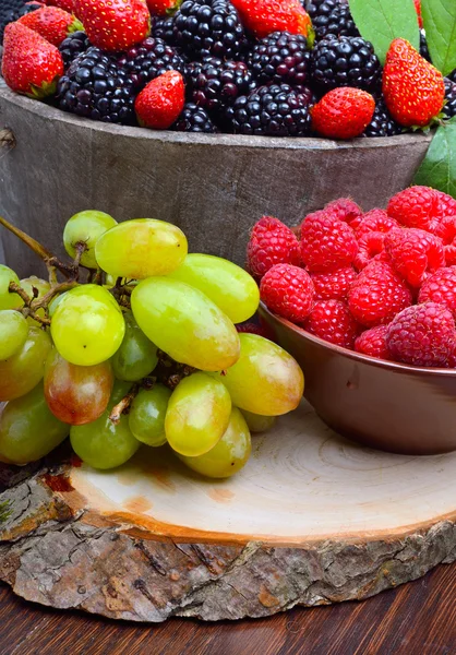 Brombeeren, Erdbeeren, Himbeeren und Trauben in einem hölzernen — Stockfoto