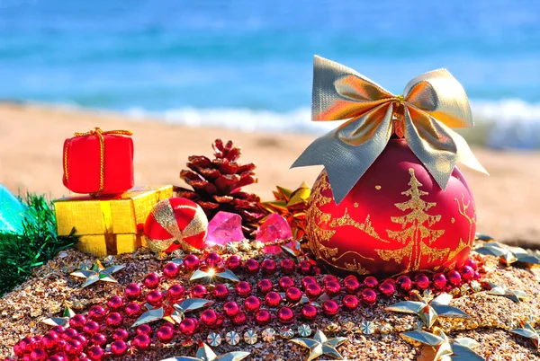 Christmas bauble on sand on beach — Stock Photo, Image