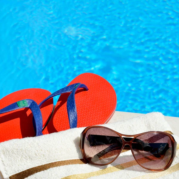 Sluneční brýle, plážový ručník a žabek u bazénu. — Stock fotografie