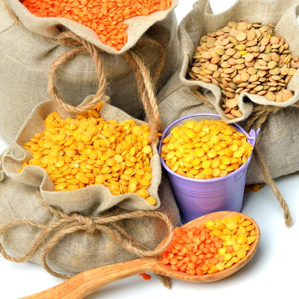 Green, red and yellow lentils in the sacks and spoon wooden isol — Stock Photo, Image