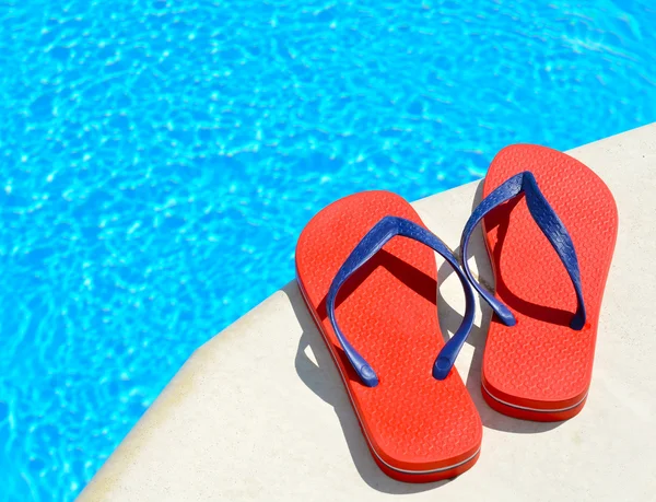 Pair of red flip-flops on the swimming pool — Stock Photo, Image