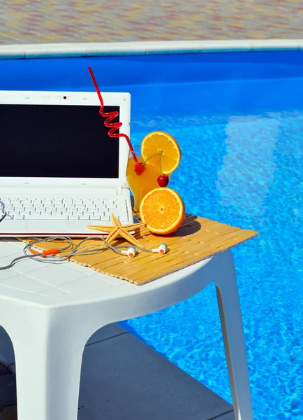 Ноутбук, навушники, коктейль біля басейну . — стокове фото