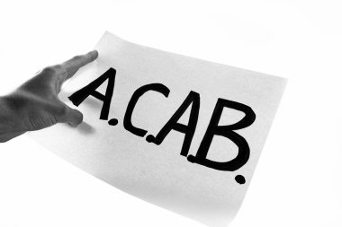Erkek el üzerinde ACAB yazıları olan bir poster tutuyor. Protestocu gösteride 