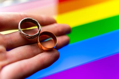 Eşcinsel evlilik teklifi. Elinde lgbt bayraklarında iki alyans var. Aynı cinsiyetten evlilik, homoseksüellik ve iki Igbt 'linin yasallaşmış ilişkisi.