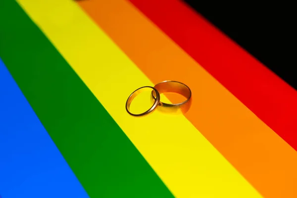 虹色のLbtの旗の上のリングのカップル Lgbtの虹の結婚指輪 同性結婚の概念 虹の背景にLgbtの結婚指輪 — ストック写真