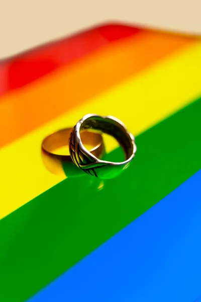 虹の旗の結婚指輪 ゲイ結婚の概念 虹色のLgbt旗の上に — ストック写真