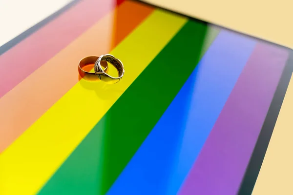 背景に虹のバナーに2つのウェディングリング Lgbtのシンボルと2人のゲイの合法的な労働組合 — ストック写真