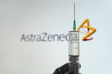 Kyiv, Ukrayna - 18 Nisan 2021: Elinizde şırınga, bulanık arkaplanda AstraZeneca logosu var. AstraZeneca ya da Oxford COVID aşı konsepti. Vatandaş kavramının aşılanması